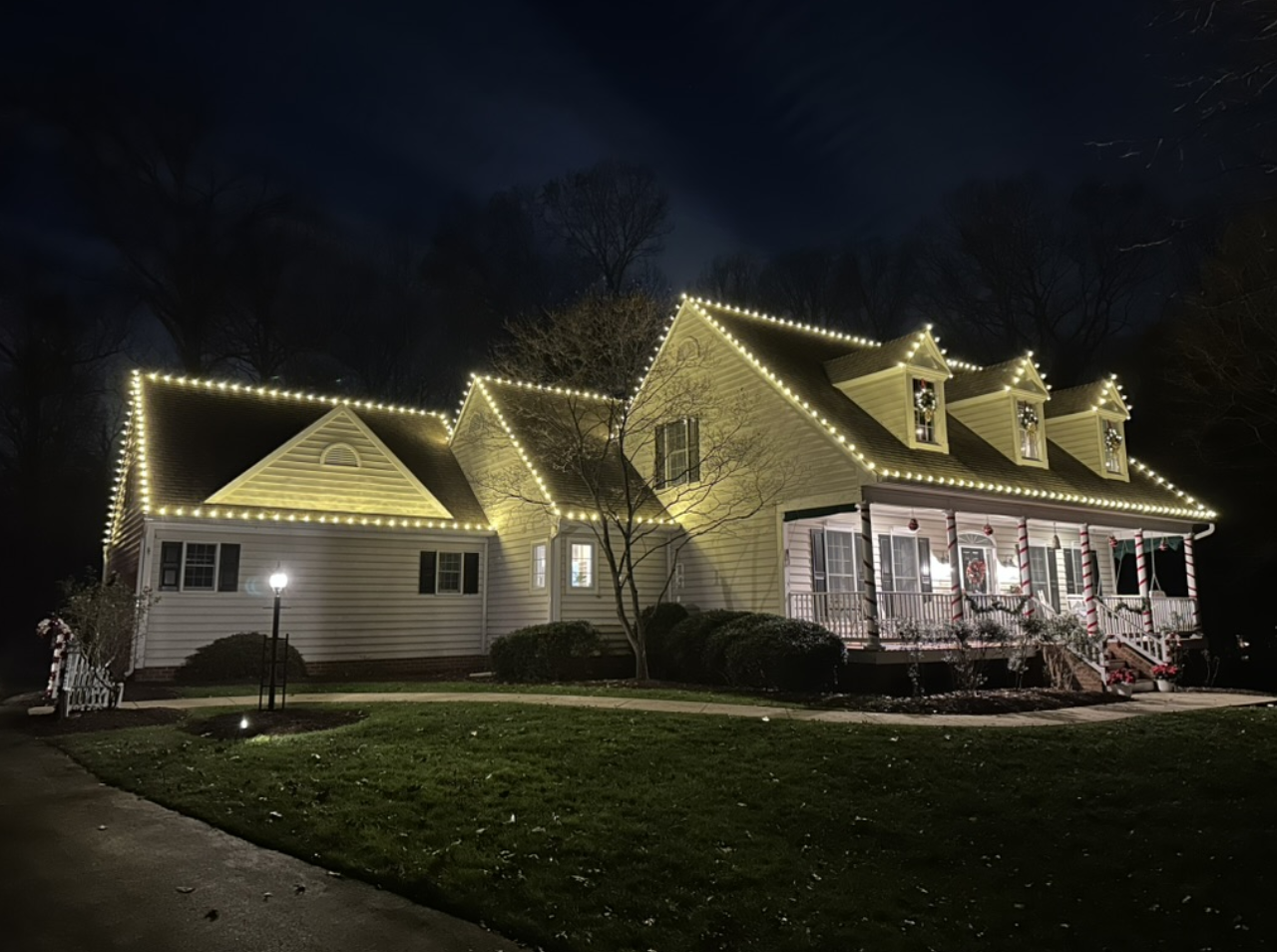 Warm white seasonal roofline lighting on a cape cod home in Maryland